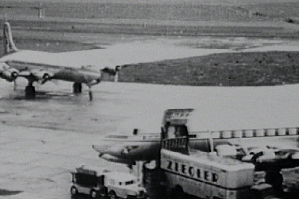 A photo of Ziegler transport vehicle loading goods onto an aircraft with another plane in the distance